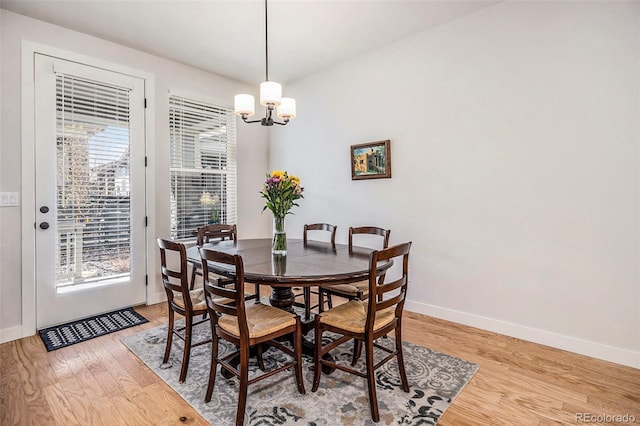 dining area with light wood-style flooring, a chandelier, baseboards, and a healthy amount of sunlight
