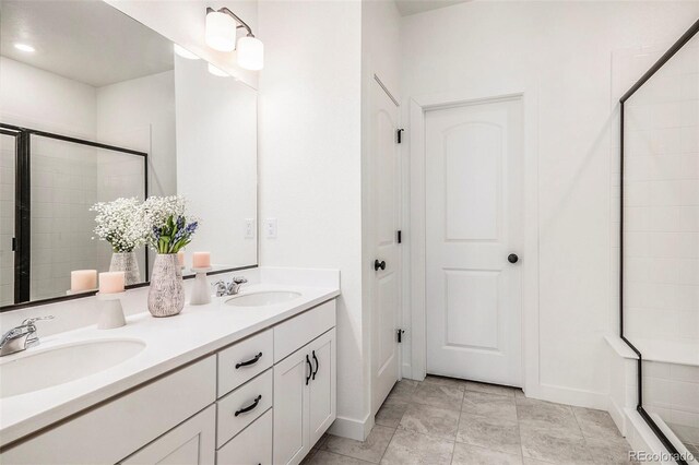 bathroom with a sink, a shower stall, and double vanity