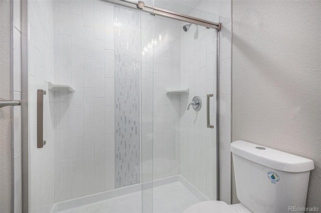 full bathroom with toilet, a stall shower, and a textured wall