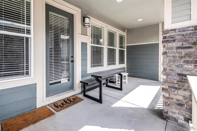 view of exterior entry with stone siding and covered porch