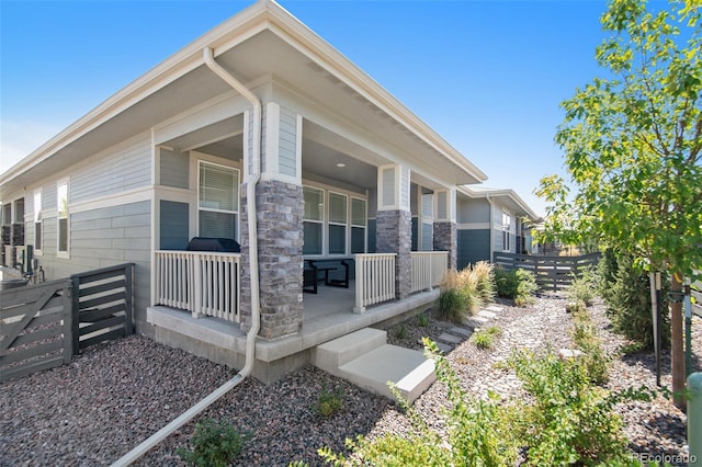view of side of home with covered porch and fence