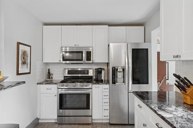 kitchen featuring stainless steel appliances, tasteful backsplash, dark stone countertops, and white cabinets