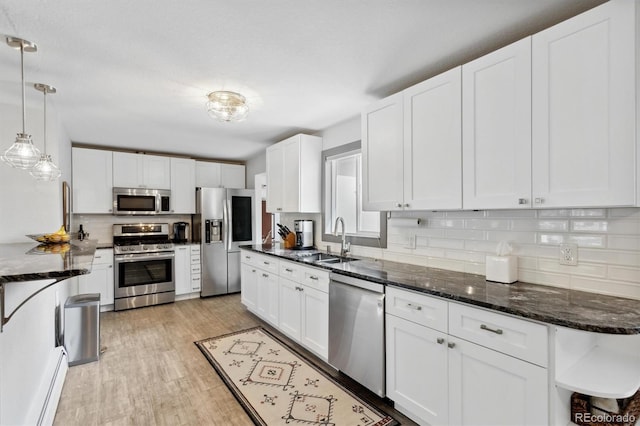 kitchen with pendant lighting, sink, white cabinets, and appliances with stainless steel finishes