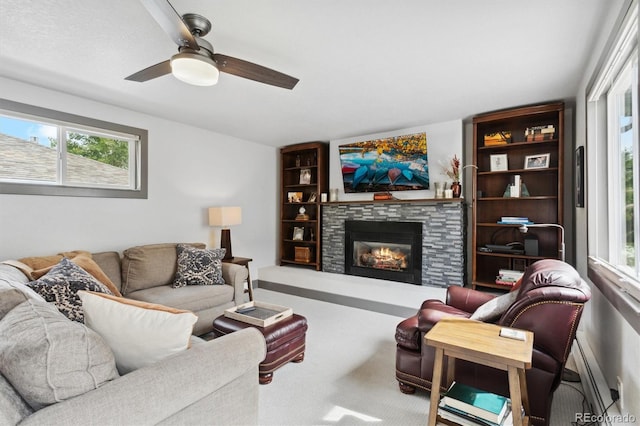 living room featuring a stone fireplace, carpet flooring, and ceiling fan