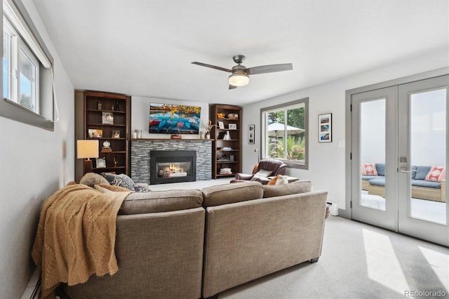 carpeted living room featuring baseboard heating, ceiling fan, a fireplace, and french doors