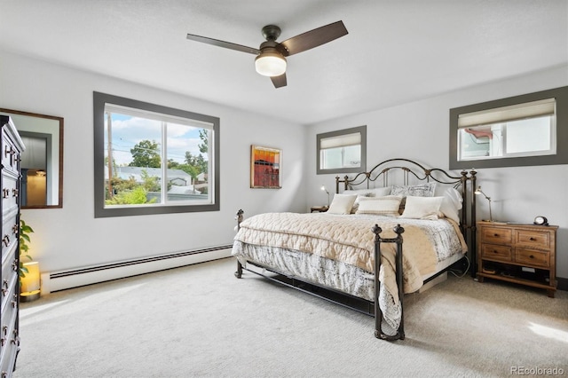 carpeted bedroom with multiple windows, a baseboard radiator, and ceiling fan