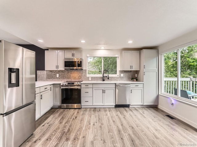 6378 S Emporia Cir, Englewood, CO 80111 - kitchen featuring appliances with stainless steel finishes, light countertops, light wood-type flooring, tasteful backsplash, and recessed lighting