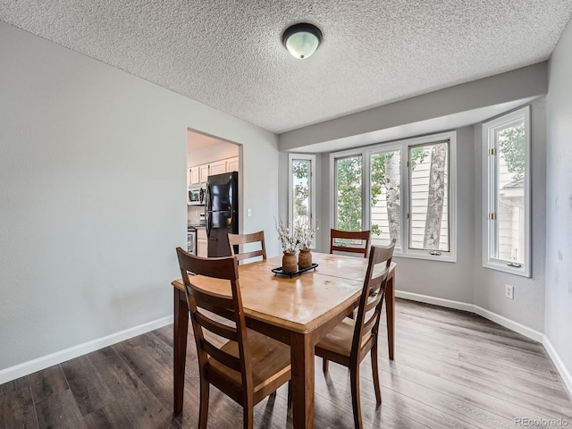 19098 E Ida Dr, Aurora, CO 80015 - dining space with plenty of natural light, wood finished floors, a textured ceiling, and baseboards