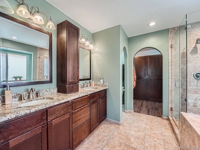 19098 E Ida Dr, Aurora, CO 80015 - full bathroom featuring double vanity, a shower stall, tile patterned floors, and a textured wall