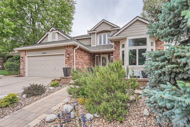 19098 E Ida Dr, Aurora, CO 80015 - view of front of house with an attached garage, driveway, a shingled roof, and brick siding