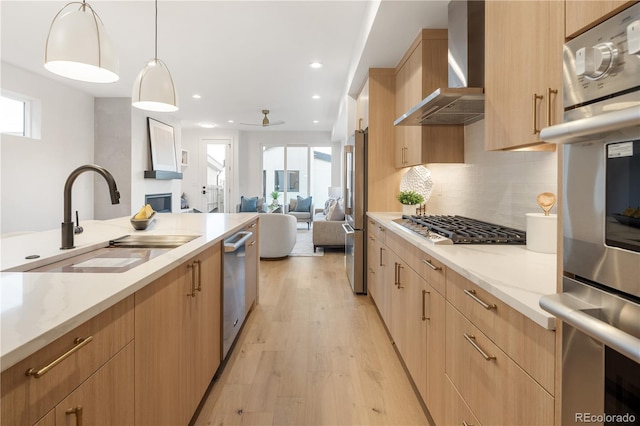 2060 Eliot St, Denver, CO 80211 - kitchen with wall chimney exhaust hood, appliances with stainless steel finishes, light wood finished floors, open floor plan, and light stone counters