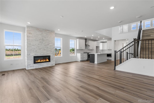8863 Springsong Ln, Littleton, CO 80125 - unfurnished living room featuring stairway, a stone fireplace, wood finished floors, and recessed lighting