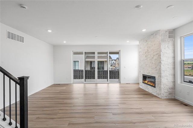 8863 Springsong Ln, Littleton, CO 80125 - unfurnished living room with wood finished floors, a stone fireplace, stairway, and recessed lighting