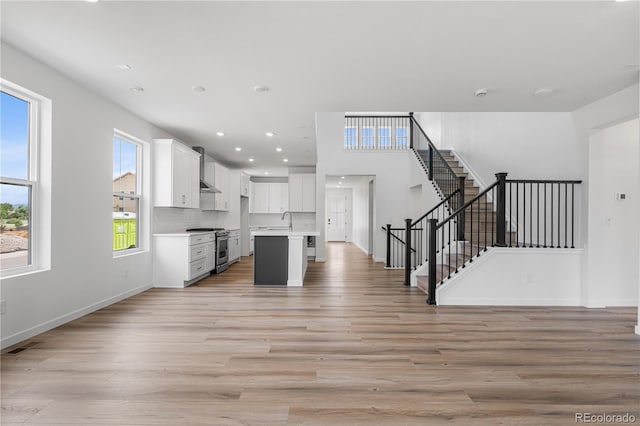 8863 Springsong Ln, Littleton, CO 80125 - kitchen with high end stainless steel range, open floor plan, light wood-style floors, light countertops, and white cabinets