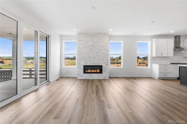 8863 Springsong Ln, Littleton, CO 80125 - unfurnished living room with light wood-style flooring, a stone fireplace, and recessed lighting