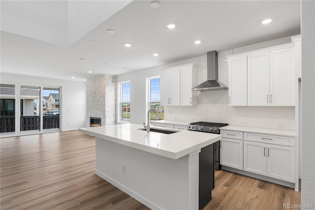 8863 Springsong Ln, Littleton, CO 80125 - kitchen with wall chimney range hood, stainless steel range with gas cooktop, healthy amount of natural light, light wood-style flooring, and recessed lighting