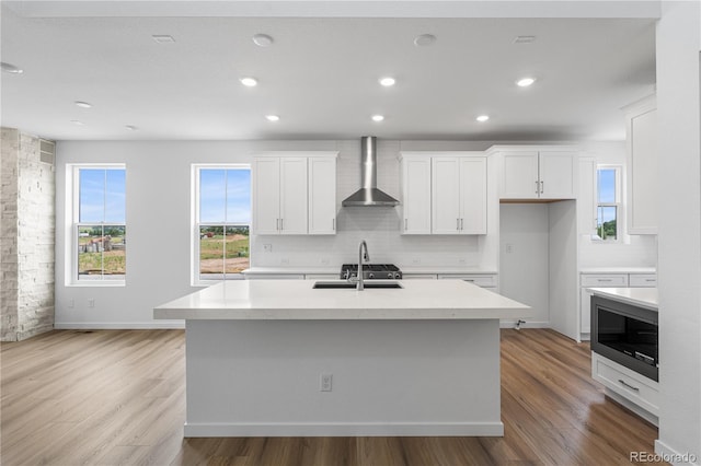 8863 Springsong Ln, Littleton, CO 80125 - kitchen with built in microwave, backsplash, white cabinetry, wall chimney exhaust hood, and light wood-style floors