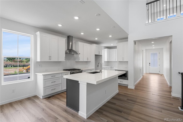 8863 Springsong Ln, Littleton, CO 80125 - kitchen with wall chimney exhaust hood, built in microwave, tasteful backsplash, recessed lighting, and wood finished floors
