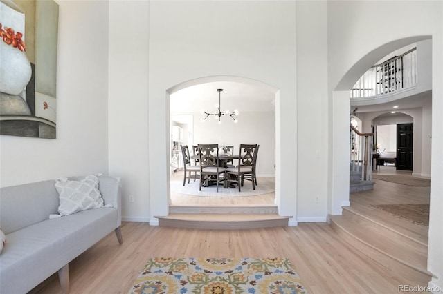 living room featuring wood-type flooring, a high ceiling, and an inviting chandelier