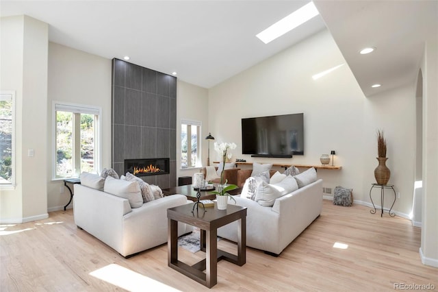 living room with light wood-type flooring, high vaulted ceiling, and a fireplace