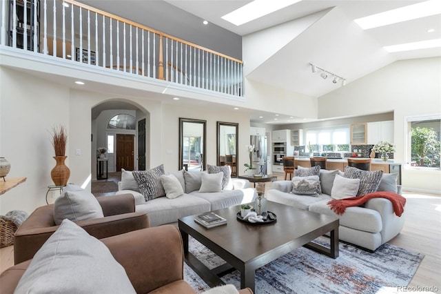 living room with high vaulted ceiling and light wood-type flooring