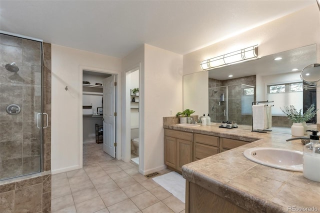 bathroom featuring a shower with door, tile patterned floors, vanity, and toilet