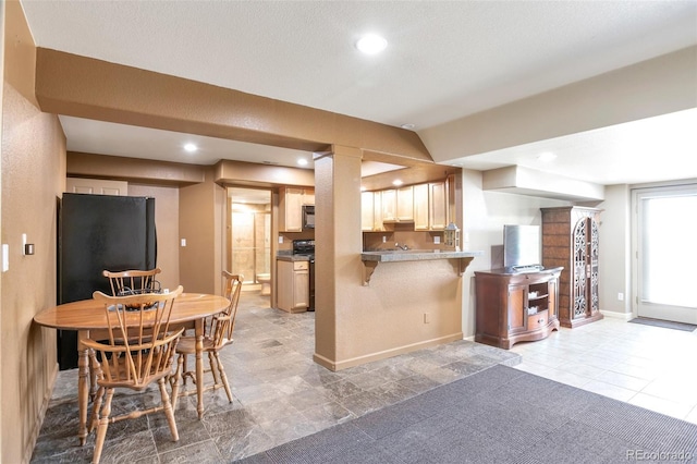 kitchen featuring vaulted ceiling, a kitchen bar, and black appliances