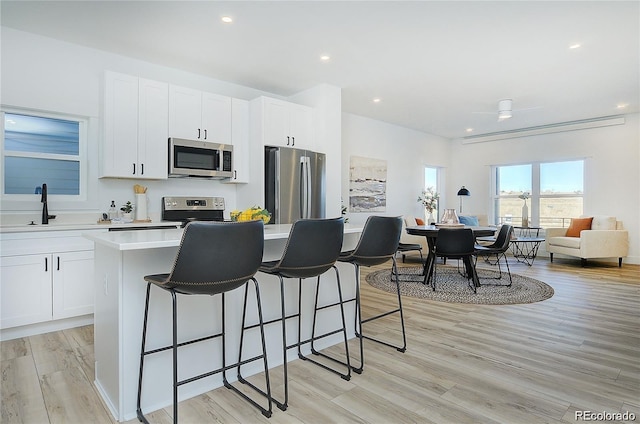 kitchen featuring a center island, sink, light hardwood / wood-style floors, white cabinetry, and stainless steel appliances