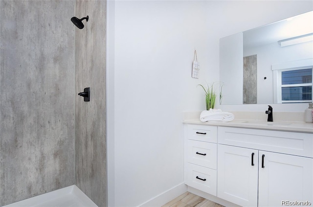 bathroom with a shower, hardwood / wood-style floors, and vanity