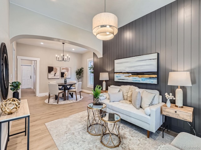 living area featuring baseboards, a notable chandelier, arched walkways, and wood finished floors