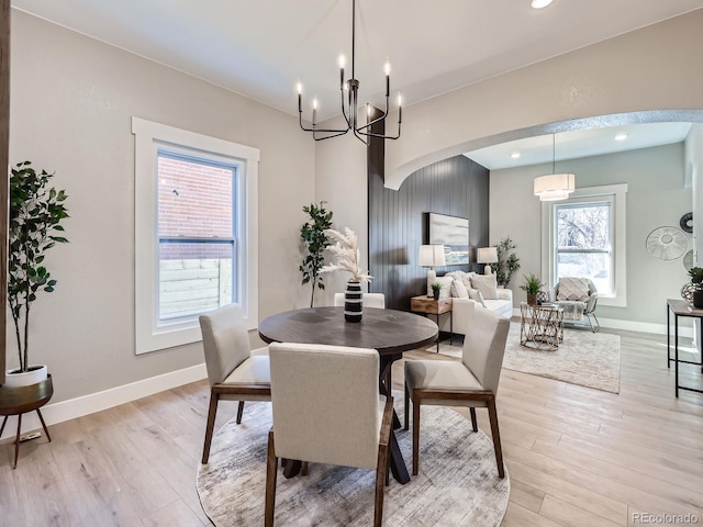 dining room with arched walkways, light wood finished floors, and baseboards