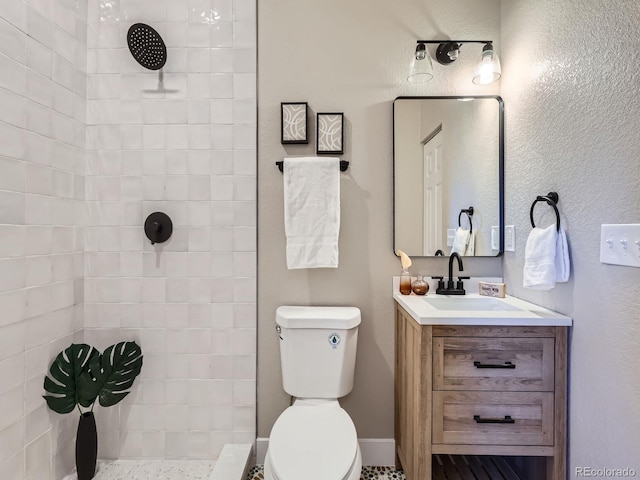 full bath featuring a tile shower, vanity, and toilet