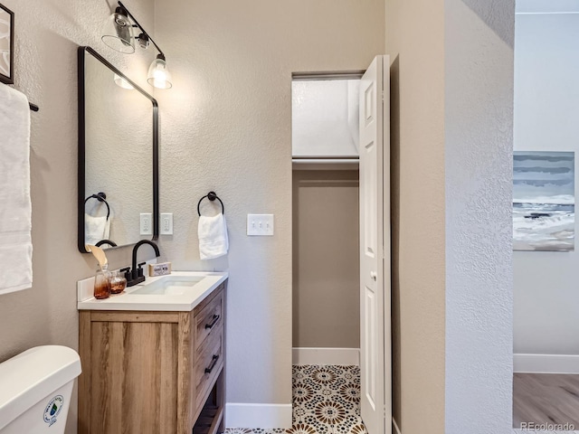 bathroom with baseboards, vanity, and toilet