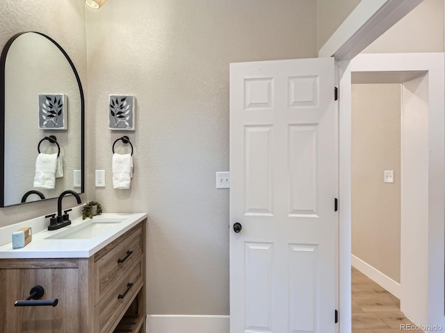 bathroom featuring vanity, baseboards, and wood finished floors