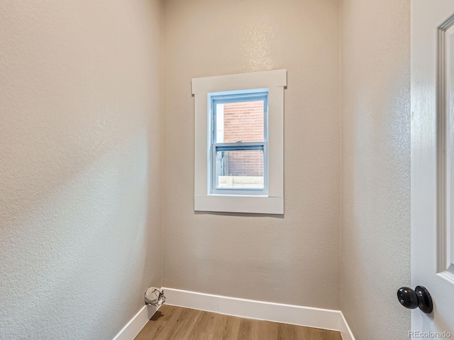 empty room featuring a textured wall, baseboards, and wood finished floors