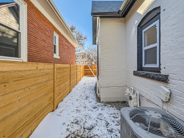 view of property exterior with roof with shingles, fence, and central AC unit