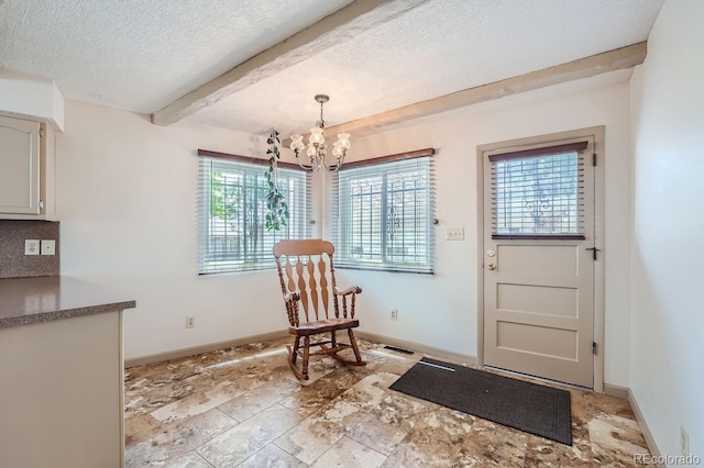 doorway with an inviting chandelier, beam ceiling, and a textured ceiling
