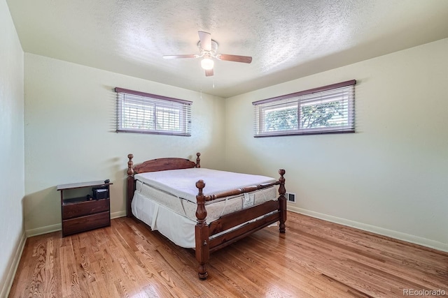 bedroom featuring ceiling fan, light hardwood / wood-style flooring, and a textured ceiling