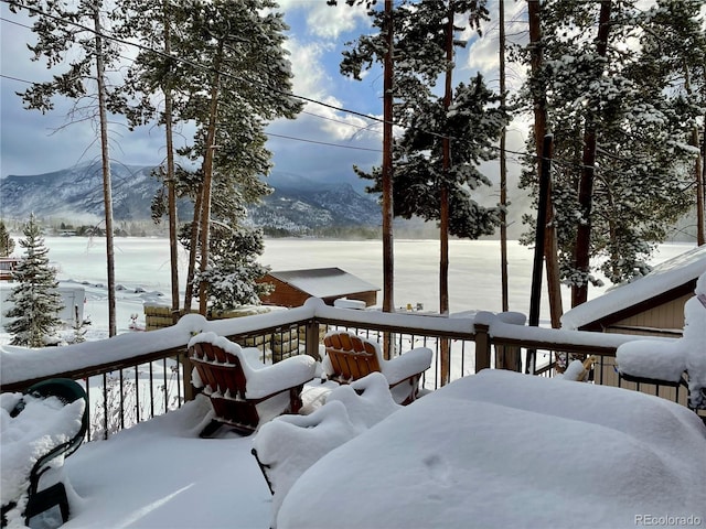 snow covered deck with a mountain view