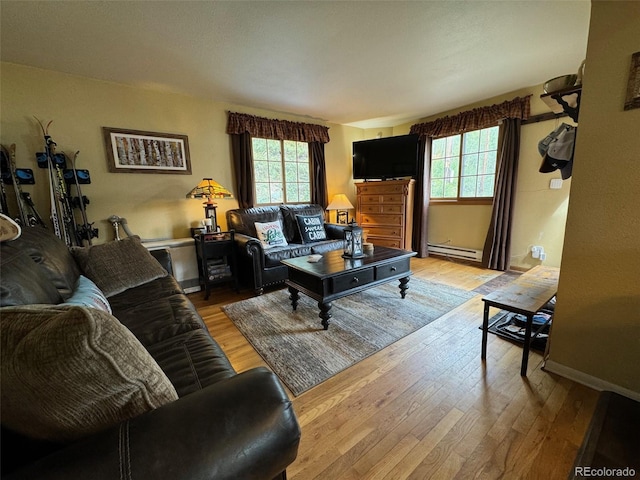 living room with light hardwood / wood-style floors, baseboard heating, and plenty of natural light