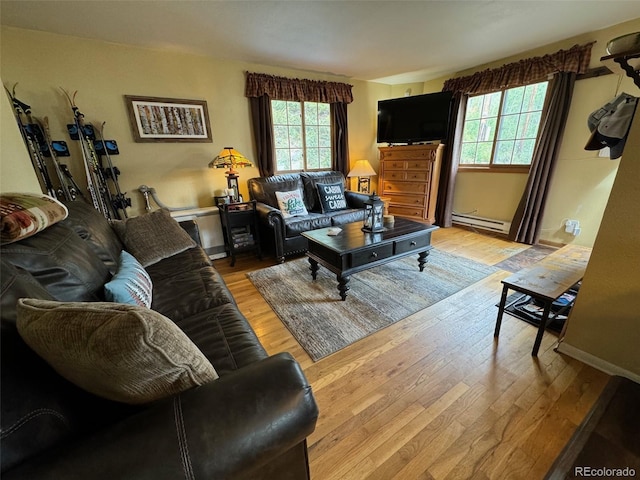 living room featuring light hardwood / wood-style flooring, baseboard heating, and a healthy amount of sunlight