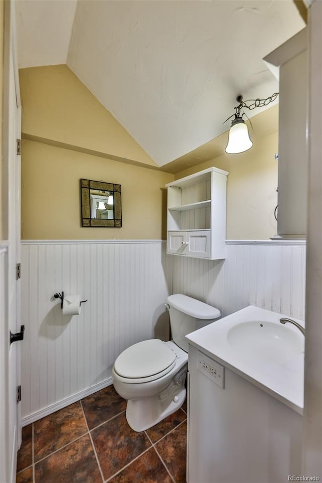 bathroom featuring vanity, toilet, and vaulted ceiling