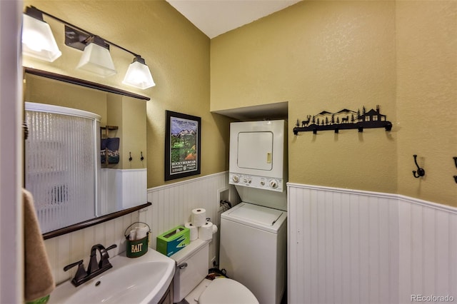 bathroom with stacked washer / dryer, sink, and toilet