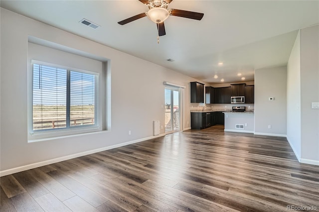 unfurnished living room featuring ceiling fan, dark hardwood / wood-style flooring, and sink