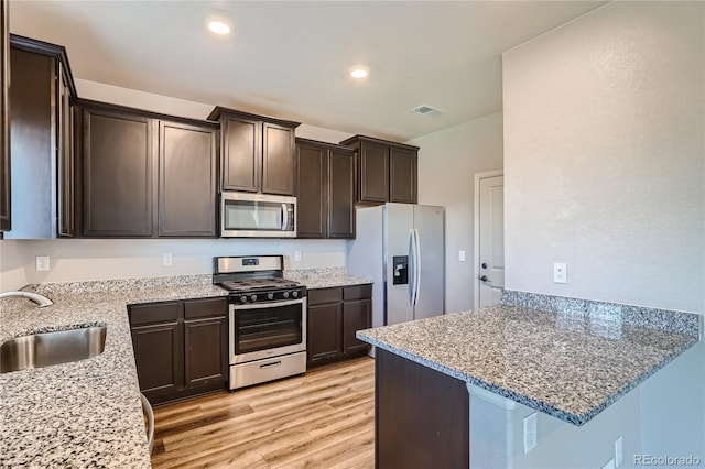 kitchen featuring light stone counters, sink, appliances with stainless steel finishes, and light hardwood / wood-style flooring