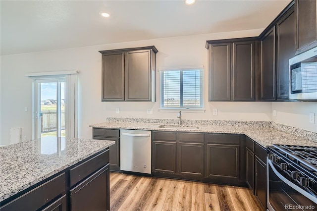 kitchen featuring dark brown cabinetry, sink, stainless steel appliances, and light wood-type flooring