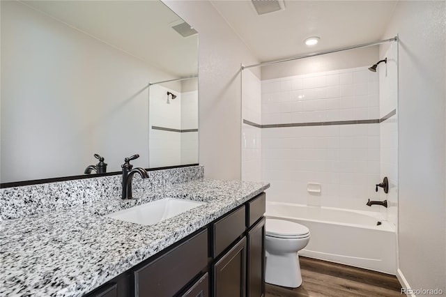 full bathroom featuring tiled shower / bath, vanity, wood-type flooring, and toilet