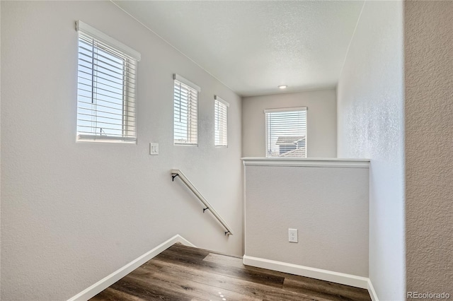 stairway with hardwood / wood-style floors and a textured ceiling