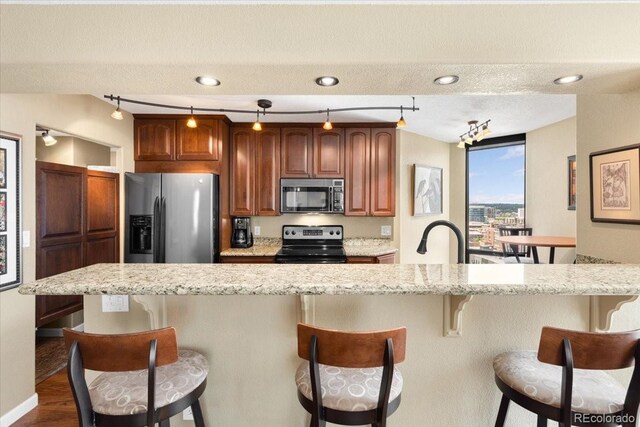 1625 Larimer St Unit 1605, Denver, CO 80202 - kitchen with black microwave, range with electric cooktop, stainless steel fridge with ice dispenser, a kitchen breakfast bar, and light stone counters