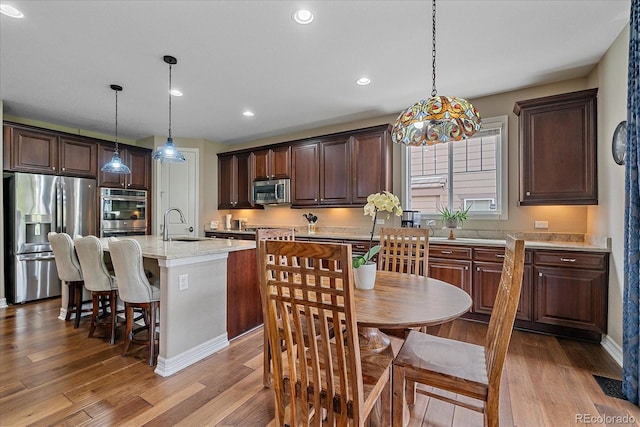 23871 E Ontario Pl, Aurora, CO 80016 - kitchen featuring appliances with stainless steel finishes, light wood-style floors, dark brown cabinetry, pendant lighting, and recessed lighting